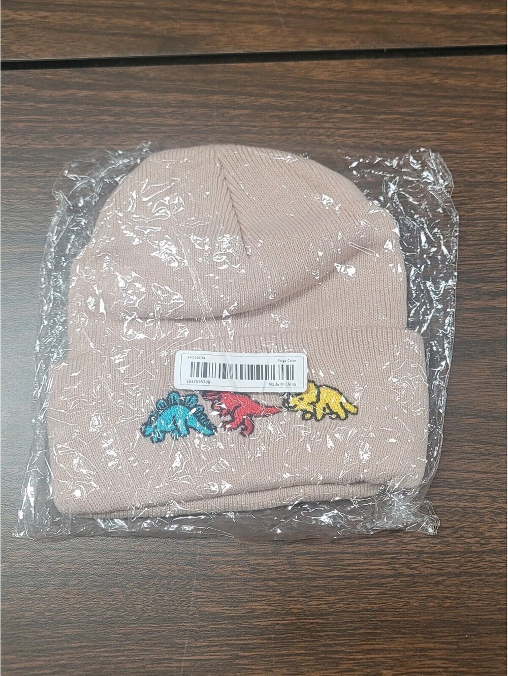 New In Package Beige Colored Beanie With Embroidered Dinosaurs